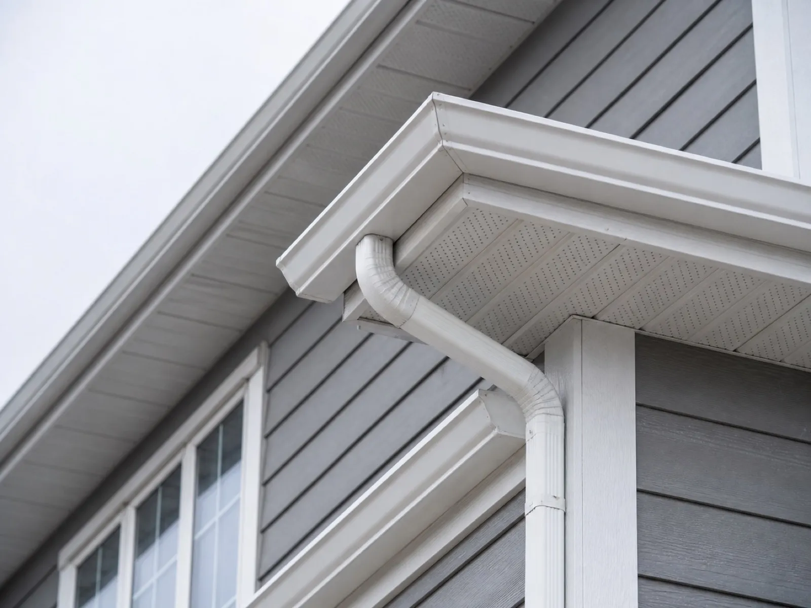 Close-up of clean white aluminum soffit, fascia and seamless eavestrough along a roofline edge